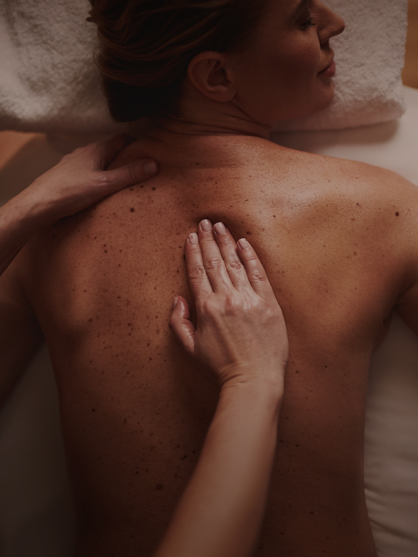 A smiling woman enjoying an expert massage service at Hand & Stone Massage and Facial Spa.